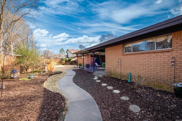 view of side of home featuring a patio area, brick siding, and a fenced backyard