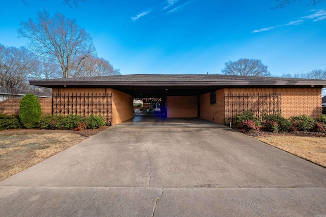 exterior space with a carport, brick siding, and driveway