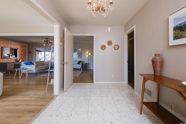 hall with light floors, visible vents, a chandelier, and baseboards