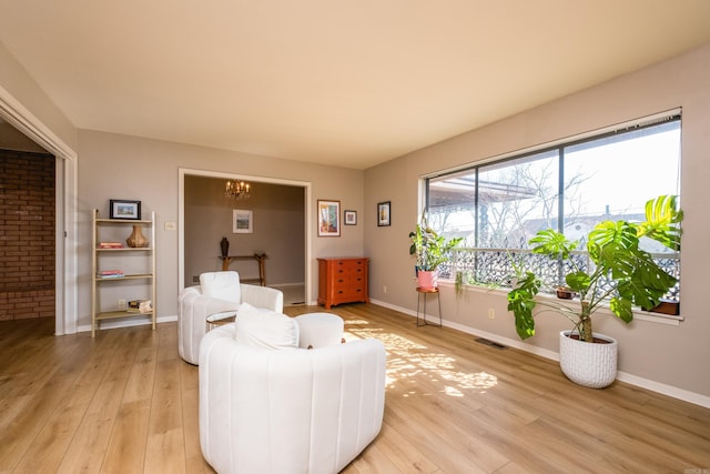 living area featuring visible vents, baseboards, light wood-style floors, and a chandelier