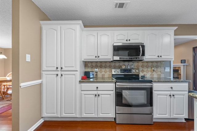 kitchen with visible vents, appliances with stainless steel finishes, white cabinetry, and wood finished floors