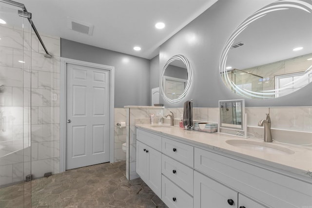 full bathroom featuring visible vents, double vanity, a stall shower, tile walls, and a sink