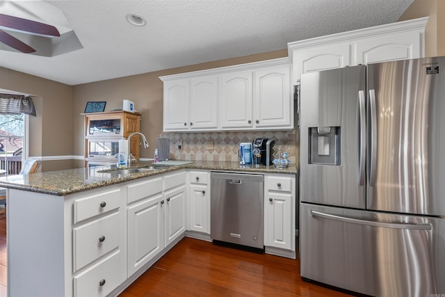 kitchen featuring a peninsula, stainless steel appliances, white cabinetry, a ceiling fan, and a sink