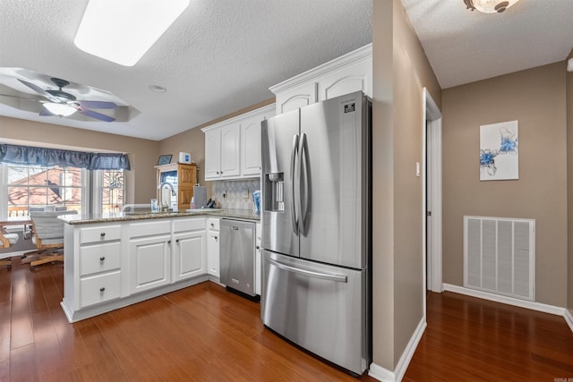 kitchen with visible vents, white cabinetry, a peninsula, and stainless steel appliances