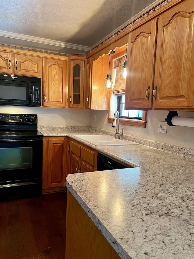 kitchen with black appliances, ornamental molding, a sink, dark wood finished floors, and light countertops