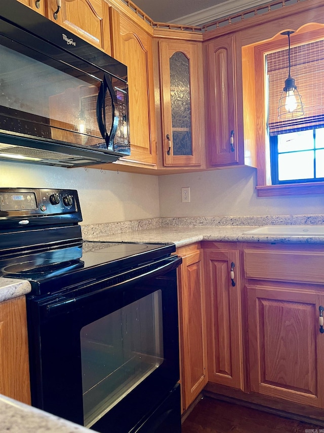 kitchen featuring brown cabinets, black appliances, a sink, light countertops, and glass insert cabinets