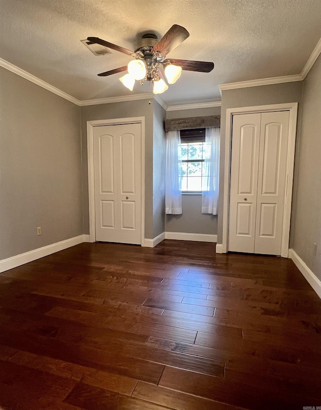 unfurnished bedroom with a textured ceiling, visible vents, dark wood-style flooring, and ornamental molding