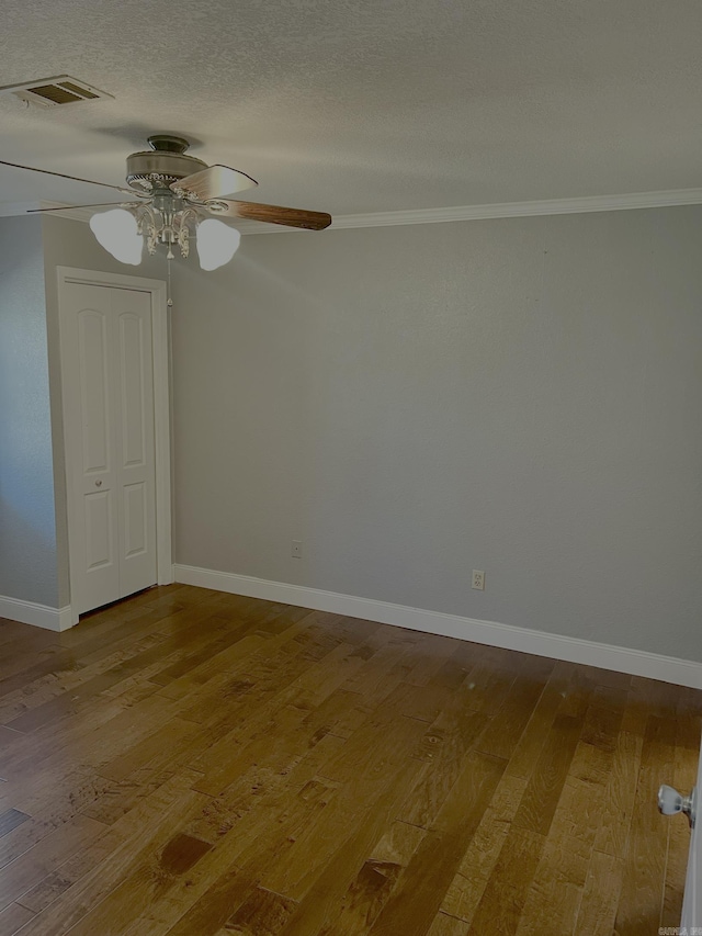 spare room featuring baseboards, visible vents, ceiling fan, wood-type flooring, and a textured ceiling