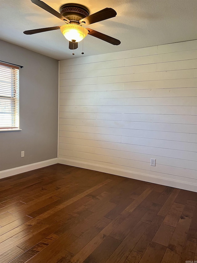 empty room featuring dark wood-style floors, a textured ceiling, baseboards, and a ceiling fan