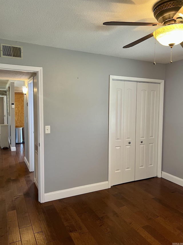 unfurnished bedroom with visible vents, baseboards, a textured ceiling, and dark wood-style flooring