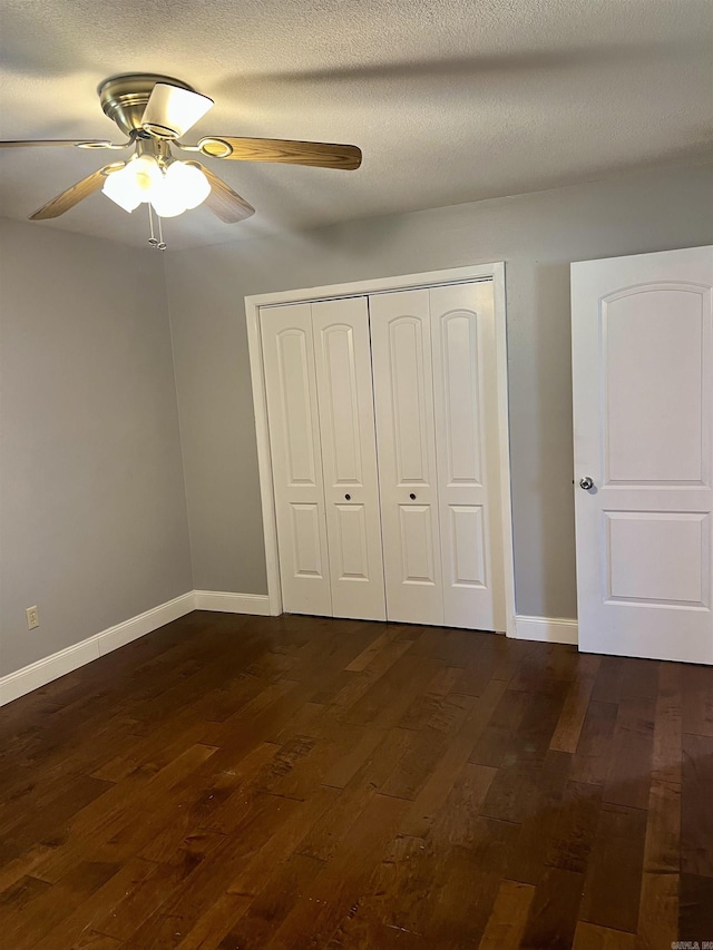 unfurnished bedroom with dark wood finished floors, baseboards, a closet, and ceiling fan