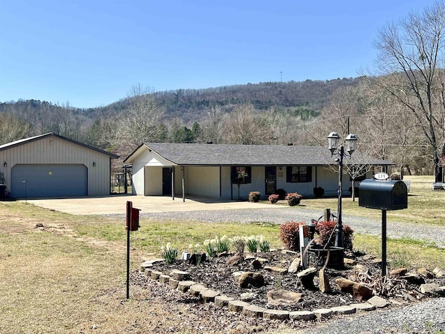 ranch-style home with a detached garage, an outdoor structure, a wooded view, and a shingled roof