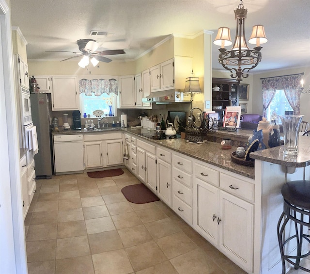 kitchen featuring crown molding, a peninsula, plenty of natural light, white appliances, and a sink