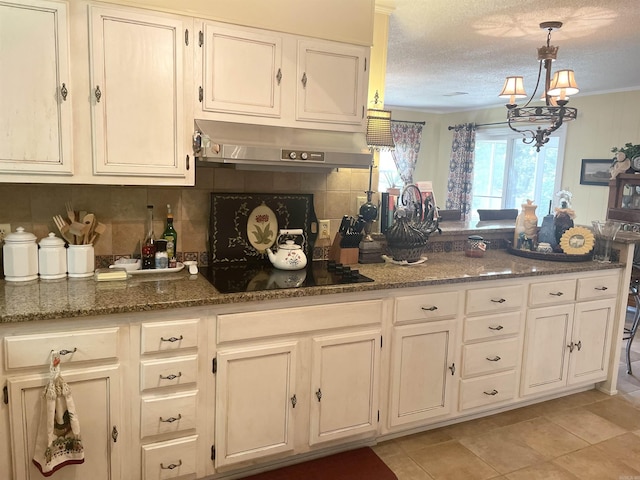 kitchen with under cabinet range hood, dark stone counters, black electric stovetop, and a peninsula