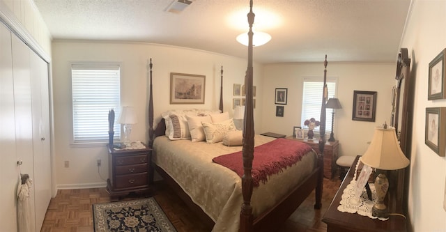 bedroom featuring baseboards, visible vents, a closet, a textured ceiling, and crown molding