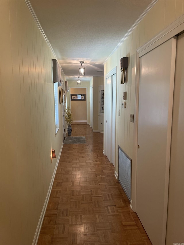 hallway with visible vents, baseboards, and ornamental molding