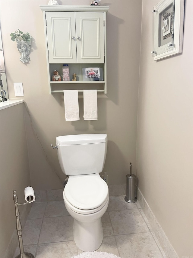 half bath with tile patterned floors, toilet, vanity, and baseboards