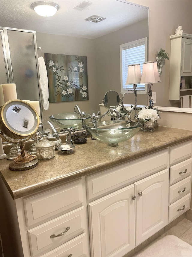 full bath with vanity, a shower stall, visible vents, and tile patterned flooring