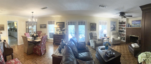 living room with visible vents, ceiling fan with notable chandelier, a fireplace, and a textured ceiling