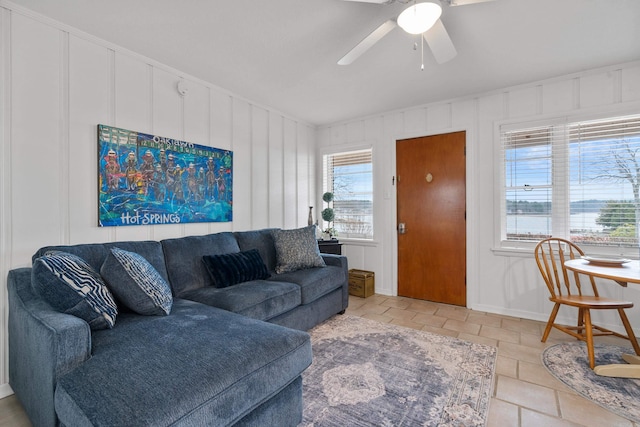 living area featuring ceiling fan, vaulted ceiling, and a decorative wall