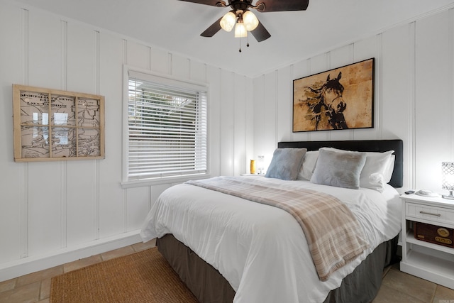 bedroom with light tile patterned floors, a ceiling fan, and a decorative wall