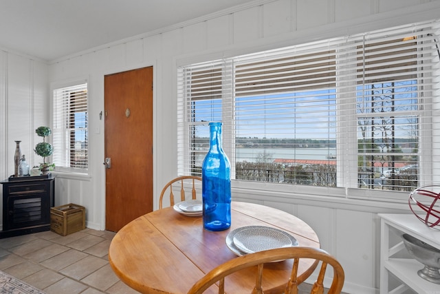 dining area featuring a decorative wall, plenty of natural light, ornamental molding, and a water view