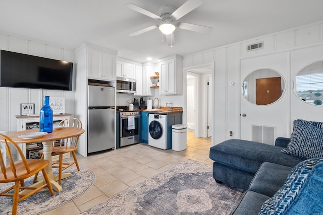 kitchen with visible vents, a sink, washer / clothes dryer, appliances with stainless steel finishes, and white cabinets