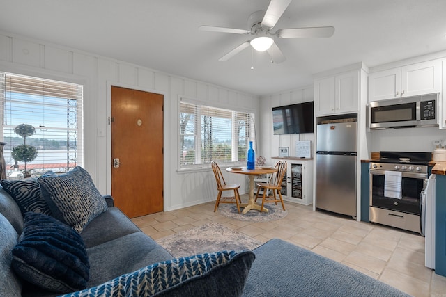 kitchen featuring stainless steel appliances, ceiling fan, light tile patterned flooring, and white cabinetry