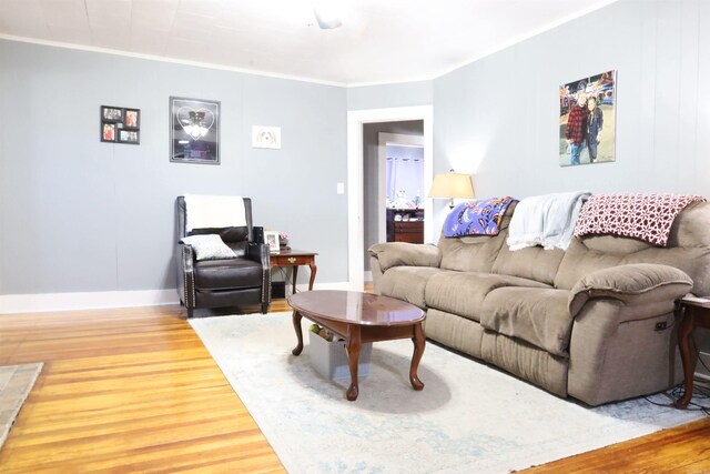 living room featuring baseboards, wood finished floors, and crown molding