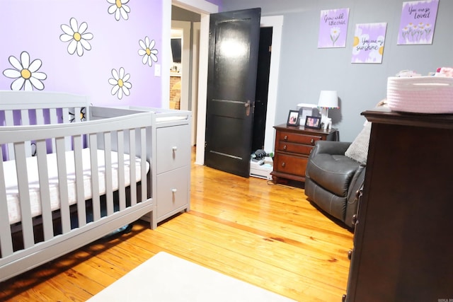 bedroom featuring a nursery area and light wood-style floors