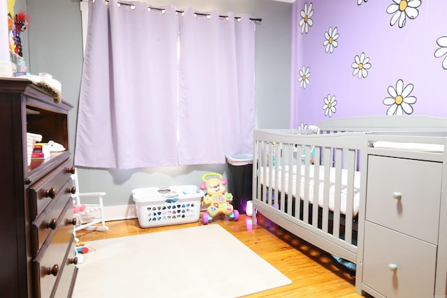 bedroom featuring a crib and wood finished floors