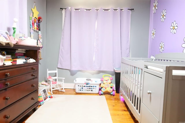 bedroom with light wood-style flooring and a nursery area