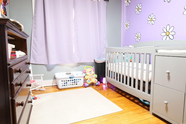 bedroom with a nursery area and wood finished floors