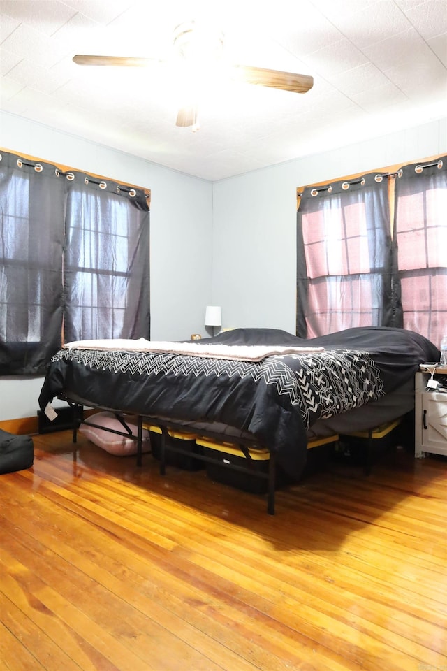 bedroom with multiple windows, light wood-style floors, and ceiling fan