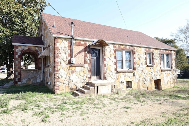 view of front of home featuring stone siding and a shingled roof