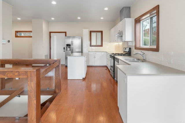 kitchen featuring a kitchen island, a sink, under cabinet range hood, appliances with stainless steel finishes, and light wood-type flooring