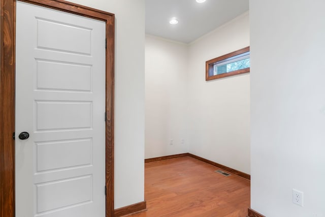 empty room featuring visible vents, baseboards, light wood-style flooring, and crown molding