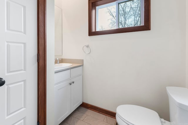 half bath with toilet, vanity, and baseboards