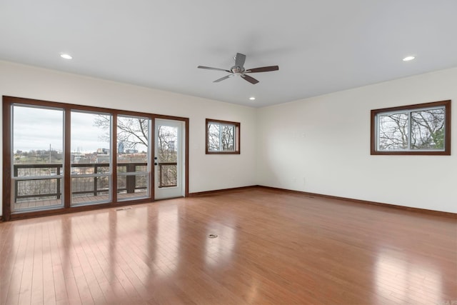 empty room featuring a healthy amount of sunlight, baseboards, and hardwood / wood-style flooring