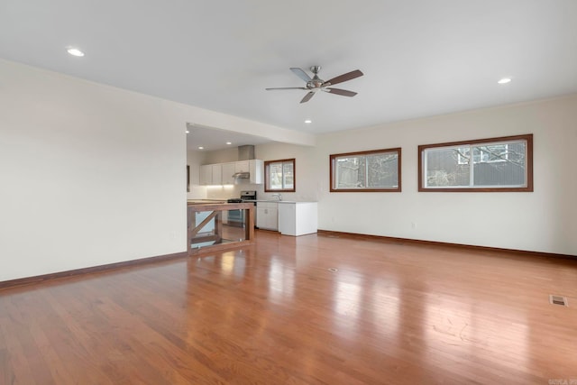 unfurnished living room featuring light wood finished floors, visible vents, and baseboards