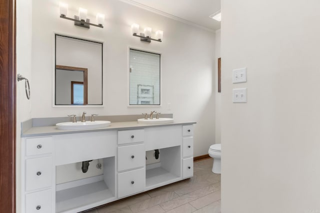 bathroom featuring double vanity, ornamental molding, toilet, and a sink