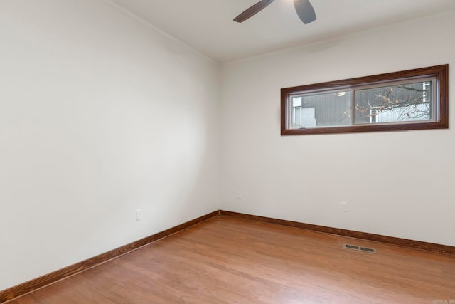 empty room featuring plenty of natural light, a ceiling fan, baseboards, and wood finished floors