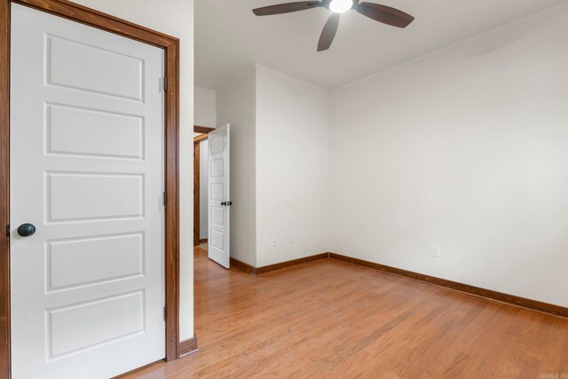 spare room featuring a ceiling fan, baseboards, and light wood finished floors