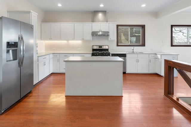 kitchen with a sink, stainless steel appliances, under cabinet range hood, and white cabinetry