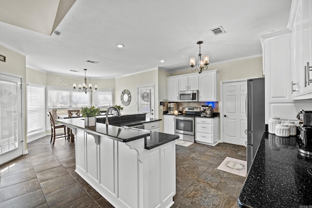 kitchen with visible vents, stone tile floors, white cabinetry, appliances with stainless steel finishes, and a chandelier