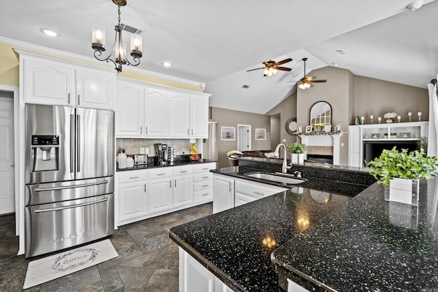 kitchen featuring decorative backsplash, a fireplace, stainless steel refrigerator with ice dispenser, white cabinetry, and a sink