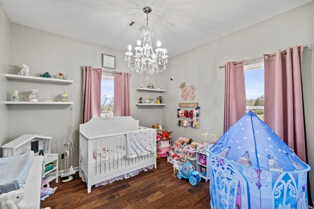 bedroom with an inviting chandelier, multiple windows, wood finished floors, and visible vents