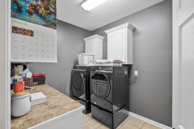 laundry room featuring washer and dryer, light tile patterned floors, cabinet space, and baseboards