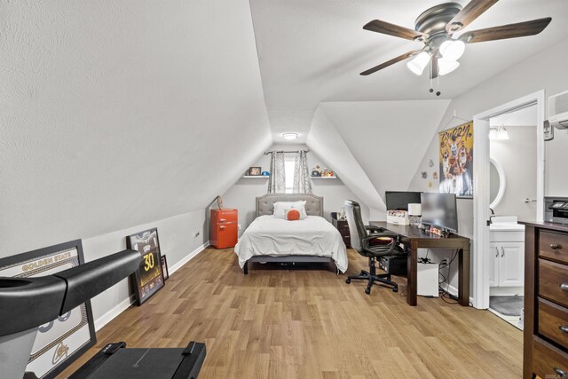 bedroom with a ceiling fan, baseboards, light wood-style flooring, vaulted ceiling, and ensuite bathroom