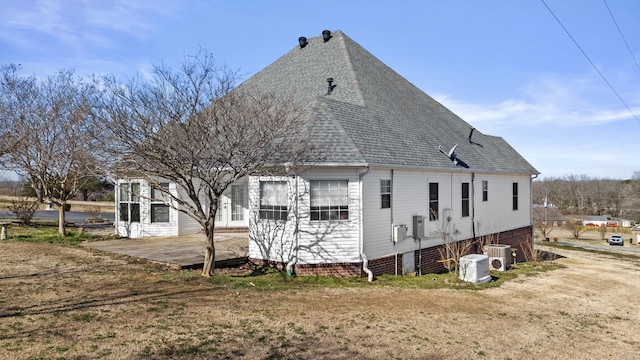 rear view of property with a yard, a patio area, and a shingled roof